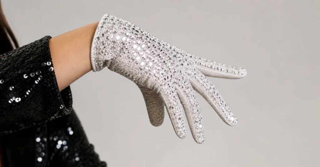 Close-up of female hand wearing sparkling white rhinestone glove in clean studio setting.