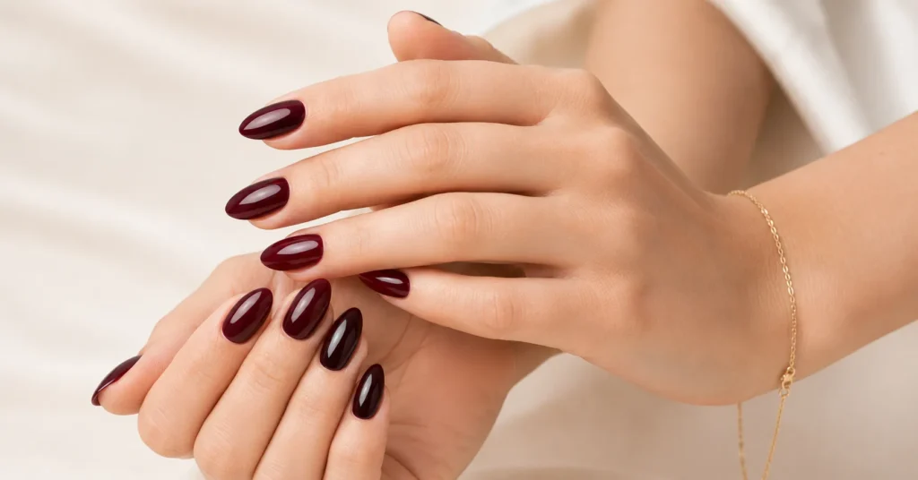 Dark winter nail colours featuring glossy black cherry nails in an almond shape.