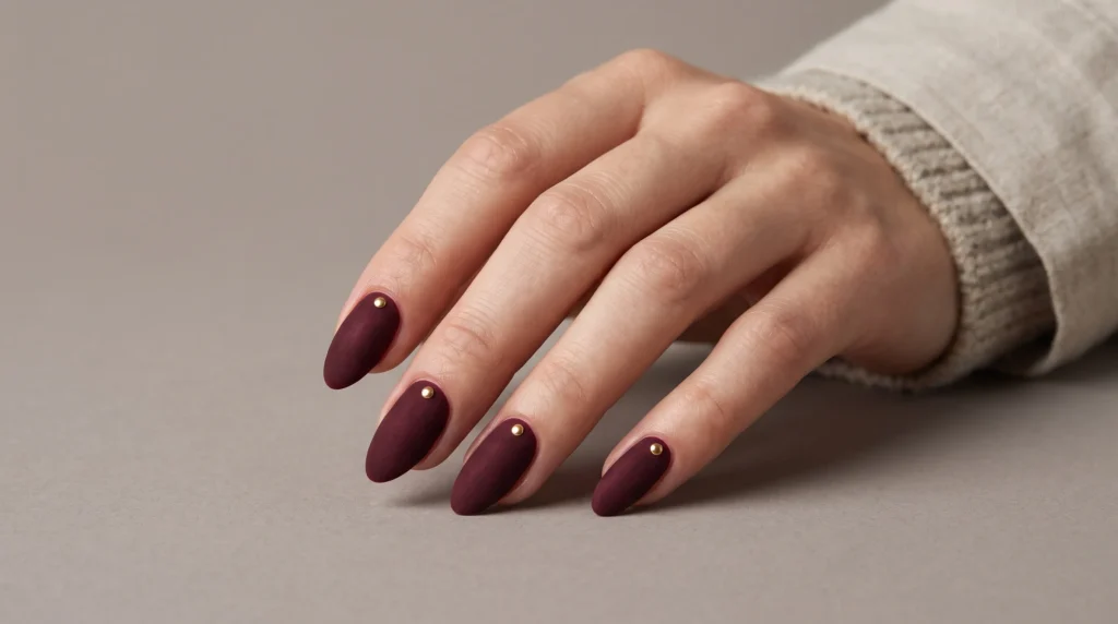 Burgundy and Gold Nails: 10 Luxurious Ideas, Shades & Pro Tips for a Rich Manicure 8 Velvety matte burgundy and gold nails accented with tiny metallic gold studs in daylight.